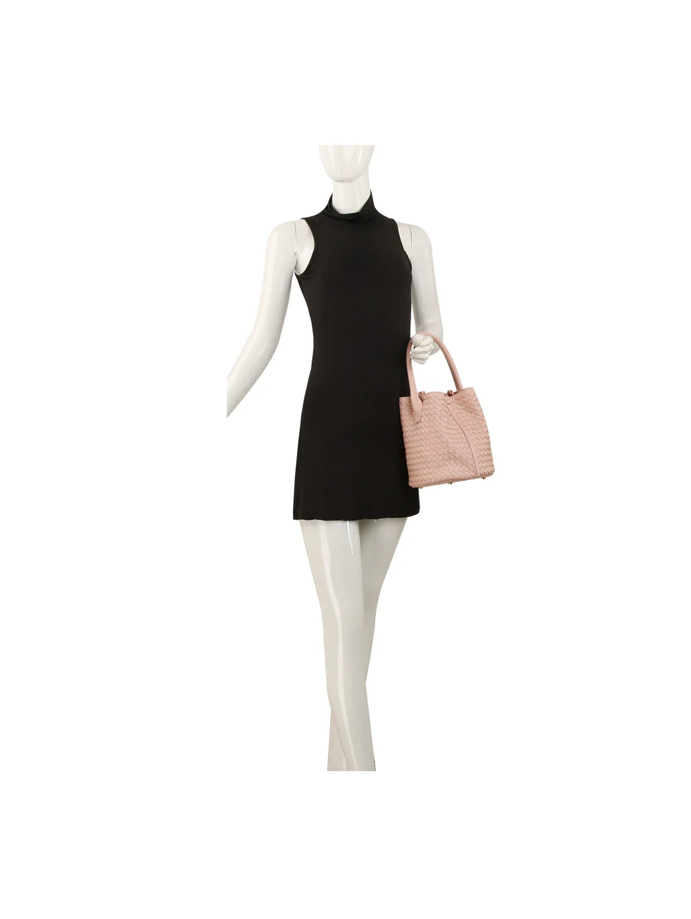 A mannequin in a sleeveless black mini dress holds the Woven Bucket Bag Two Piece Set, a light pink textured faux leather handbag with gold-toned hardware and two handles, against a plain white background.