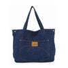 The Front Pocket Large Denim Tote is a dark blue, double-handle bag with tan abstract-stitched front pocket, brown Lec patch, silver rivet accents, and is tablet compatible for modern style and function.