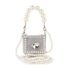 The Pearl And Rhinestone Accented Ultra Petite Evening Bag features silver faux leather, rhinestone accents, a heart-shaped gem, pearl beaded handle, and extra strap—perfect for adding sparkling glamour to any outfit.