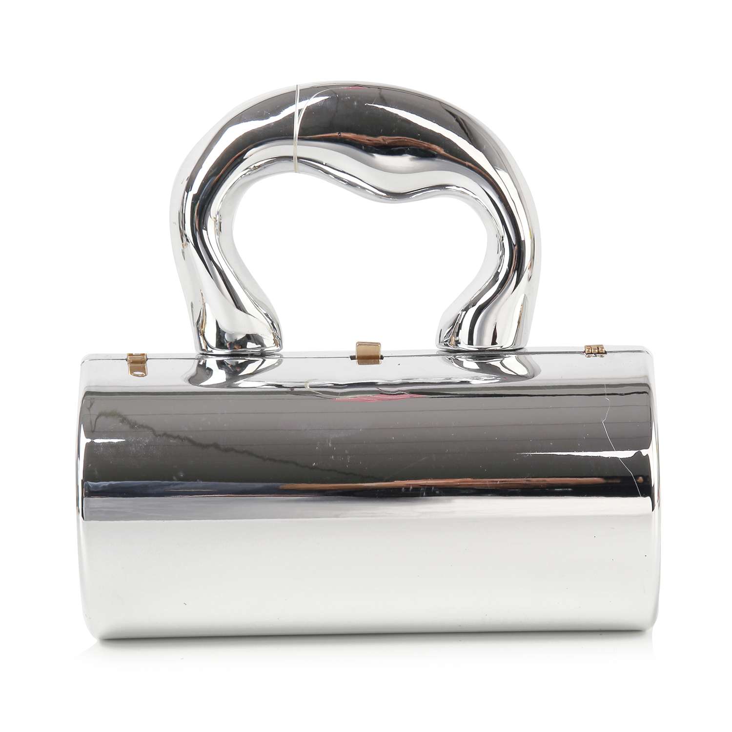 The Patent Petite Evening Bag features a shiny metallic silver finish, a sculptural Art Deco handle, and a cylindrical faux leather body that reflects light beautifully.