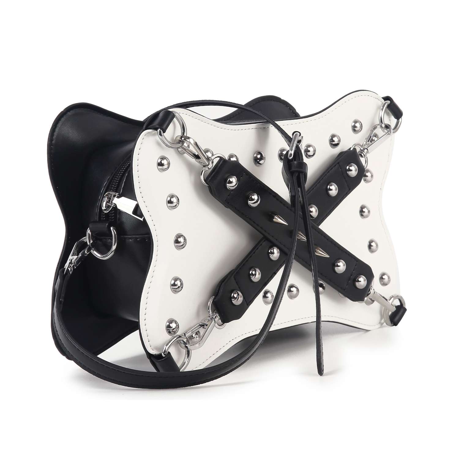 The Studded Belted Shoulder Bag features black and white faux leather, silver hardware, metal studs, crisscrossed black straps on the front, a curved structured shape, zip pocket detail, and a long shoulder strap.