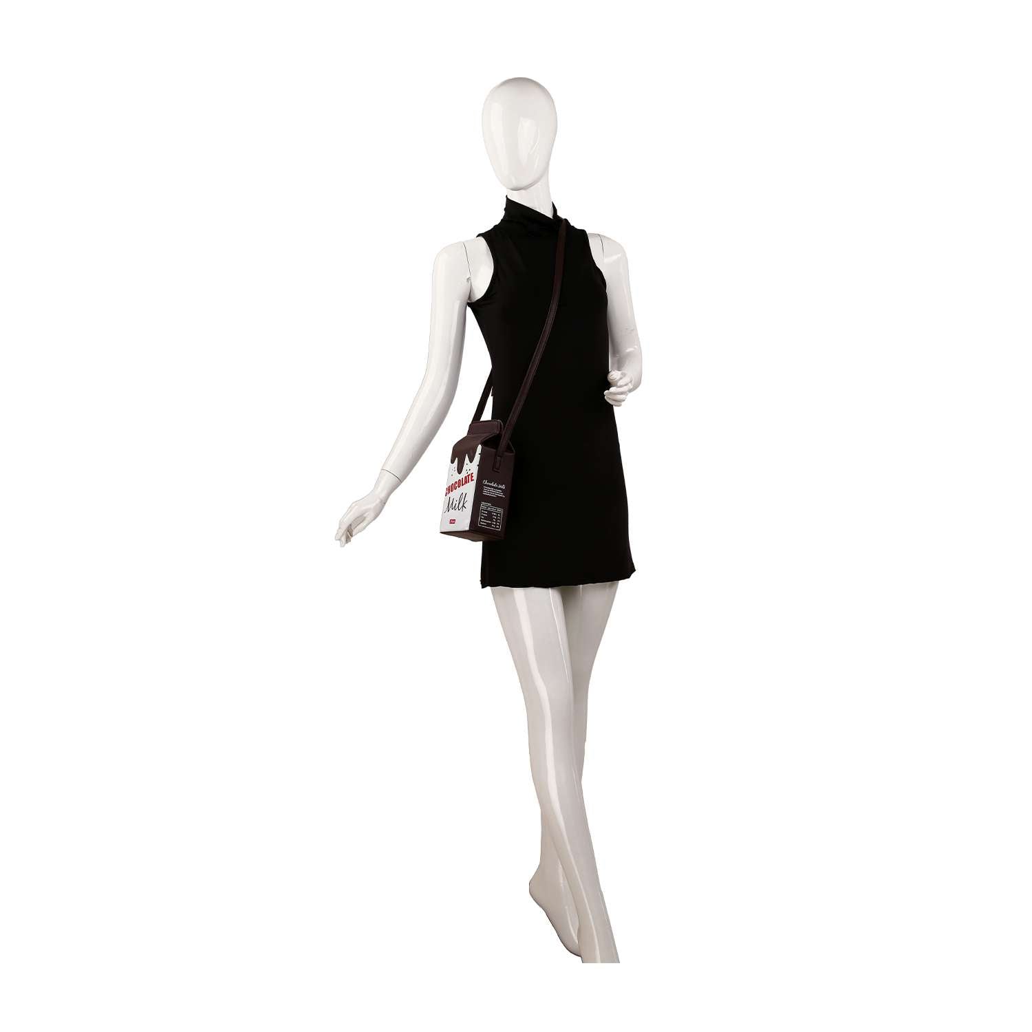 A white mannequin in a sleeveless, short black dress holds the Cute Carton Style Shoulder Bag, a faux leather crossbody shaped like a milk carton with printed text and graphics, hanging from its left shoulder by a single strap. The background is plain white.