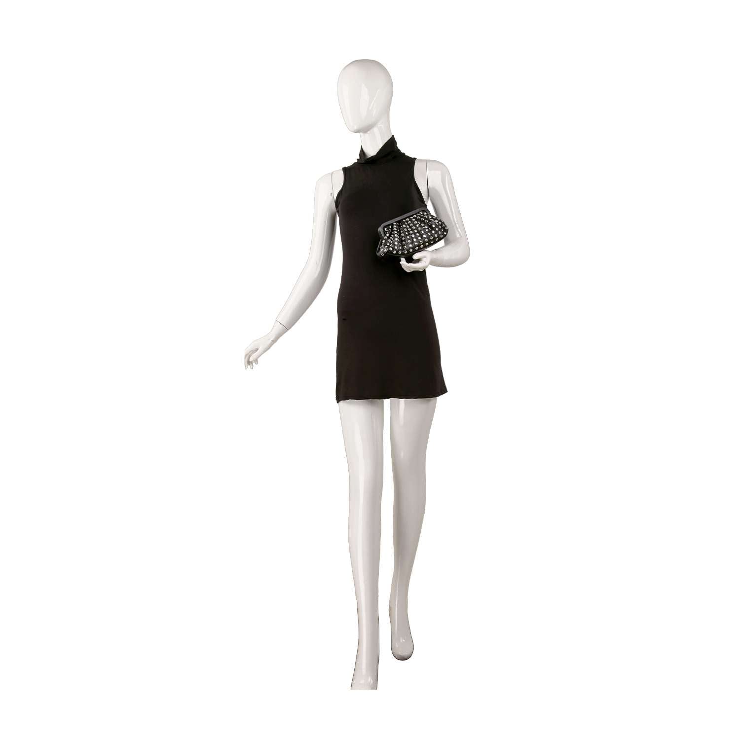 A mannequin in a sleeveless black mini dress holds the Pleated Stud Accented Clutch Bag under one arm against a plain white background.