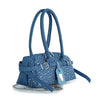 The Rhinestone Belted Hand Tote is a blue denim shoulder bag with silver studs, two long handles, belt straps, a blue luggage tag, and a silver chain strap, shown on a white background.