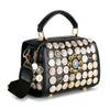The Intricate Button Design Satchel Handbag is a black faux leather bag with gold-tone hardware, ornate gold and silver button embellishments, a top handle, and a detachable shoulder strap.