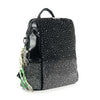 The Glamorous Stone Design Fashion Backpack is a black faux leather bag with small silver studs in a gradient pattern, a top handle, black accents, and keychains with ribbons and a silver figure on one side.