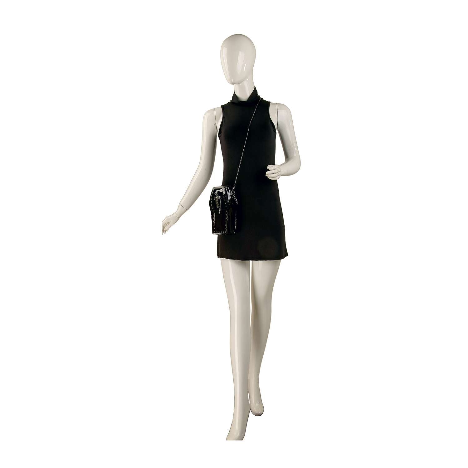 A mannequin in a sleeveless black mini dress with a high neckline carries the Coffin Design Cross Accented Clear Petite Bag, stadium approved, against a white background.