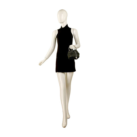 A mannequin in a sleeveless black mini dress holds the Denim Tiny Stone Accented Drawstring Bag in its left hand. The background is plain white.