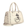 The Cross And Stud Accented Petite Satchel Handbag is cream-colored faux leather with silver studs, double handles, and metal hardware. A black studded cross and crown design accents the front. Includes a detachable strap for versatile carry.