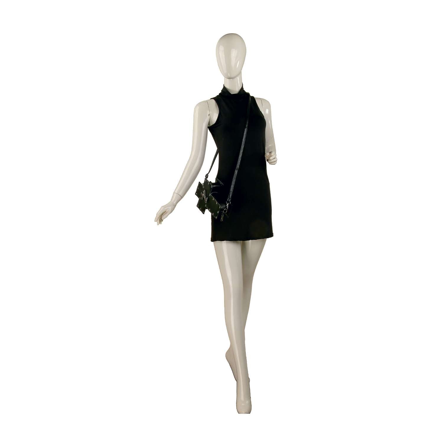 A mannequin in a sleeveless, short black dress carries the Decorative Cross Design Crossbody Bag with an adjustable strap, posed against a plain white background.