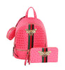 The Decorative Bee Backpack Set features a vibrant pink faux leather backpack with textured pattern, gold zippers, green-red-black striped bands, jeweled bee brooches, a matching wallet, and a small round pouch attached to the side.