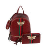 The Decorative Bee Backpack Set includes a red textured faux leather backpack with green and red stripes, a matching wallet, a small round pouch, and a bee brooch adorned with pearl and gold accents.