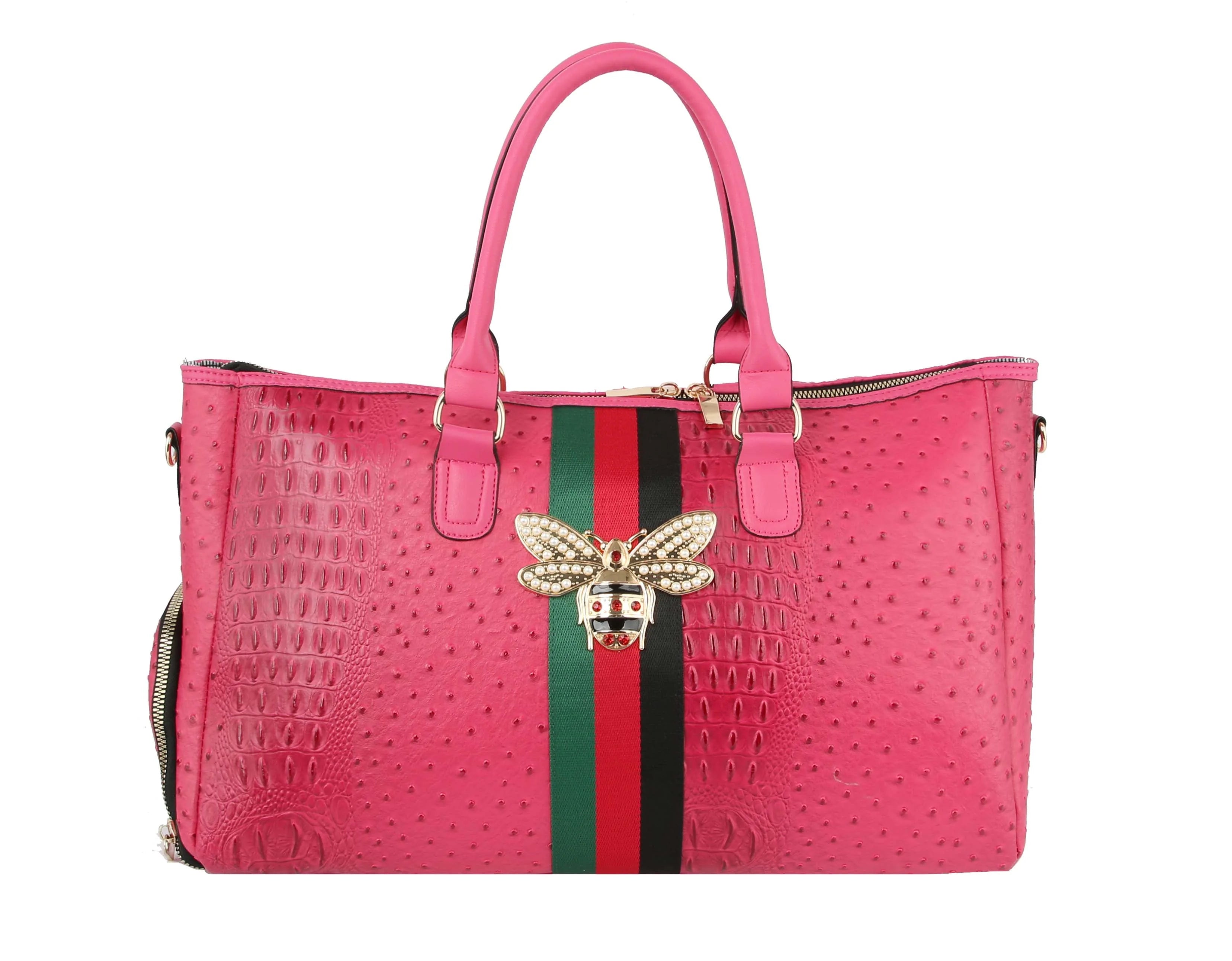 The Croc Embossed Rhinestone Bee Weekender is a pink faux leather handbag with a textured finish, dual handles, green and red vertical stripe, gold-toned hardware, jeweled bee center embellishment, and a detachable strap for versatile styling.