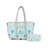 The Crest Emblem Classic Tote is a light blue bag with twin handles, featuring royal blue, white, and gray monogram and fleur-de-lis designs. It doubles as a detachable crossbody and includes a matching zippered wallet.