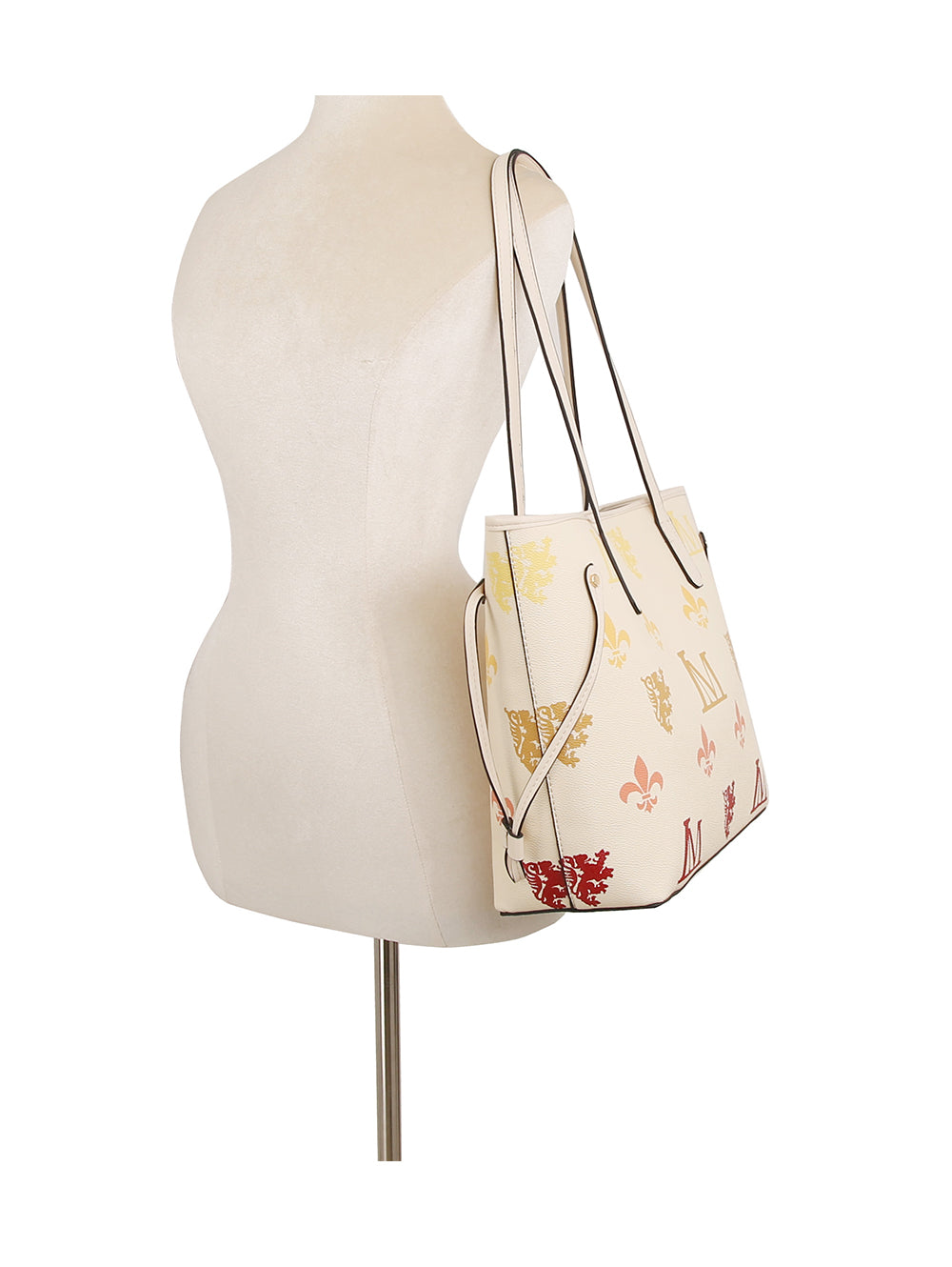 A white mannequin displays the Monogram Print Lux Faux Leather 2-Piece Tote Set in cream with multicolored symbols, black trim, two handles, structured sides, and a top zip closure against a plain white background.