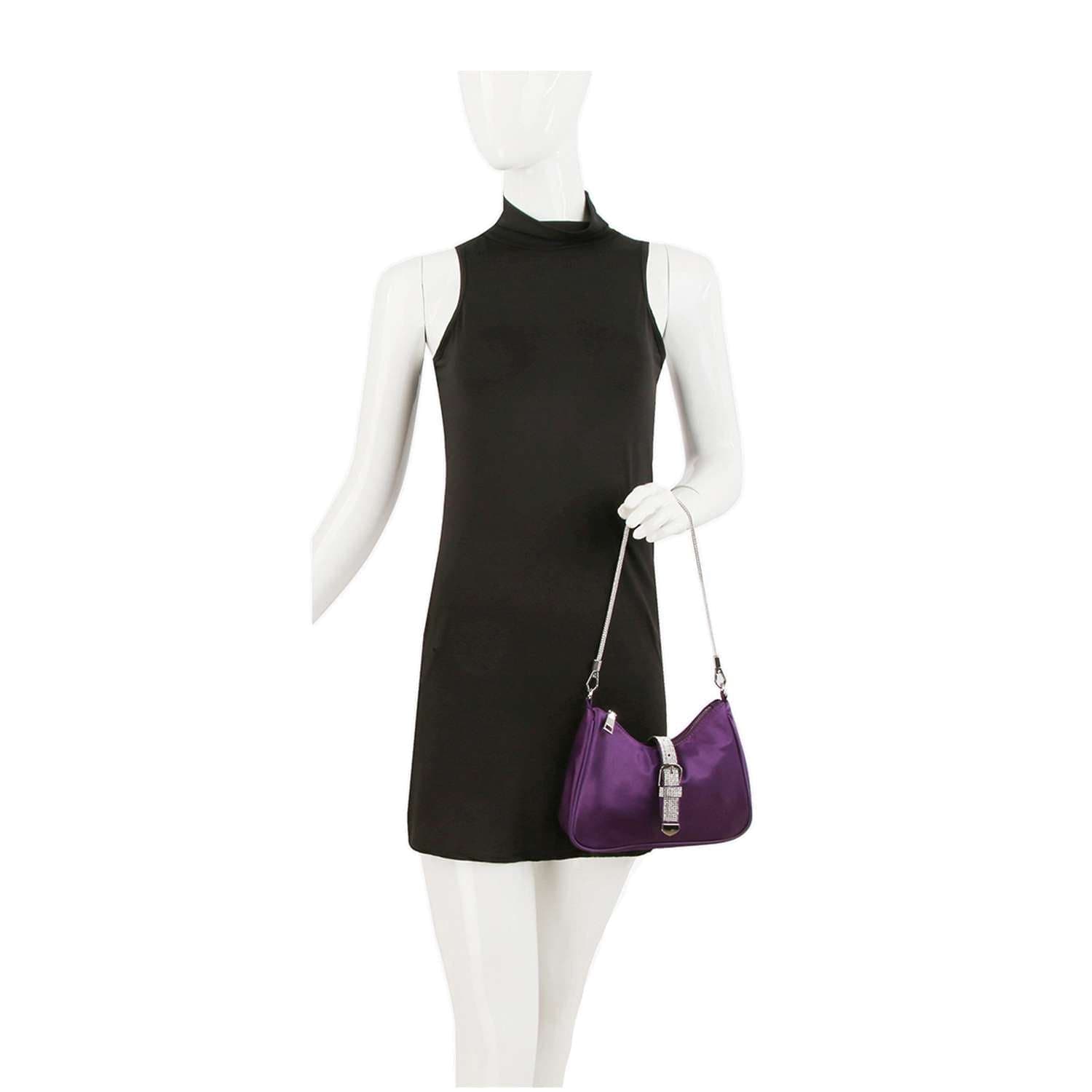 A mannequin in a sleeveless, high-neck black mini dress holds the Rhinestone Buckle Hobo Handbag—a small purple shoulder bag with a sparkling buckle and chain strap—against a plain white background.