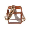 The Guitar Strap Clear Crossbody Bag is a small, transparent backpack with brown leather trim, gold zippers, and a detachable tan and black geometric guitar strap. Its visible interior adds modern flair to this stylish purse.