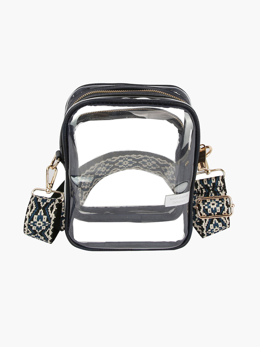 The Guitar Strap Clear Crossbody Bag is a rectangular transparent zip handbag with black trim, gold hardware, and a detachable black-and-white geometric woven strap, shown both inside the bag and attached externally.