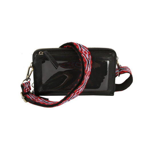 The Petite Multi Compartment Guitar Strap Crossbody is a black faux leather bag with a clear front pocket, gold-tone hardware, and zipper closure. Its wide detachable strap features bold red, white, and black patterns for style.