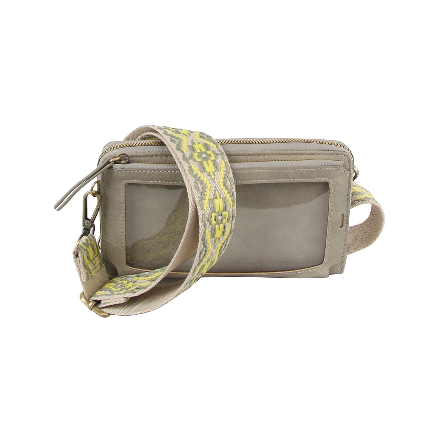 The Petite Multi Compartment Guitar Strap Crossbody is a small beige faux leather bag with a clear front window pocket, wide patterned yellow and gray strap, zipper closure, and detachable strap with metal clasps.