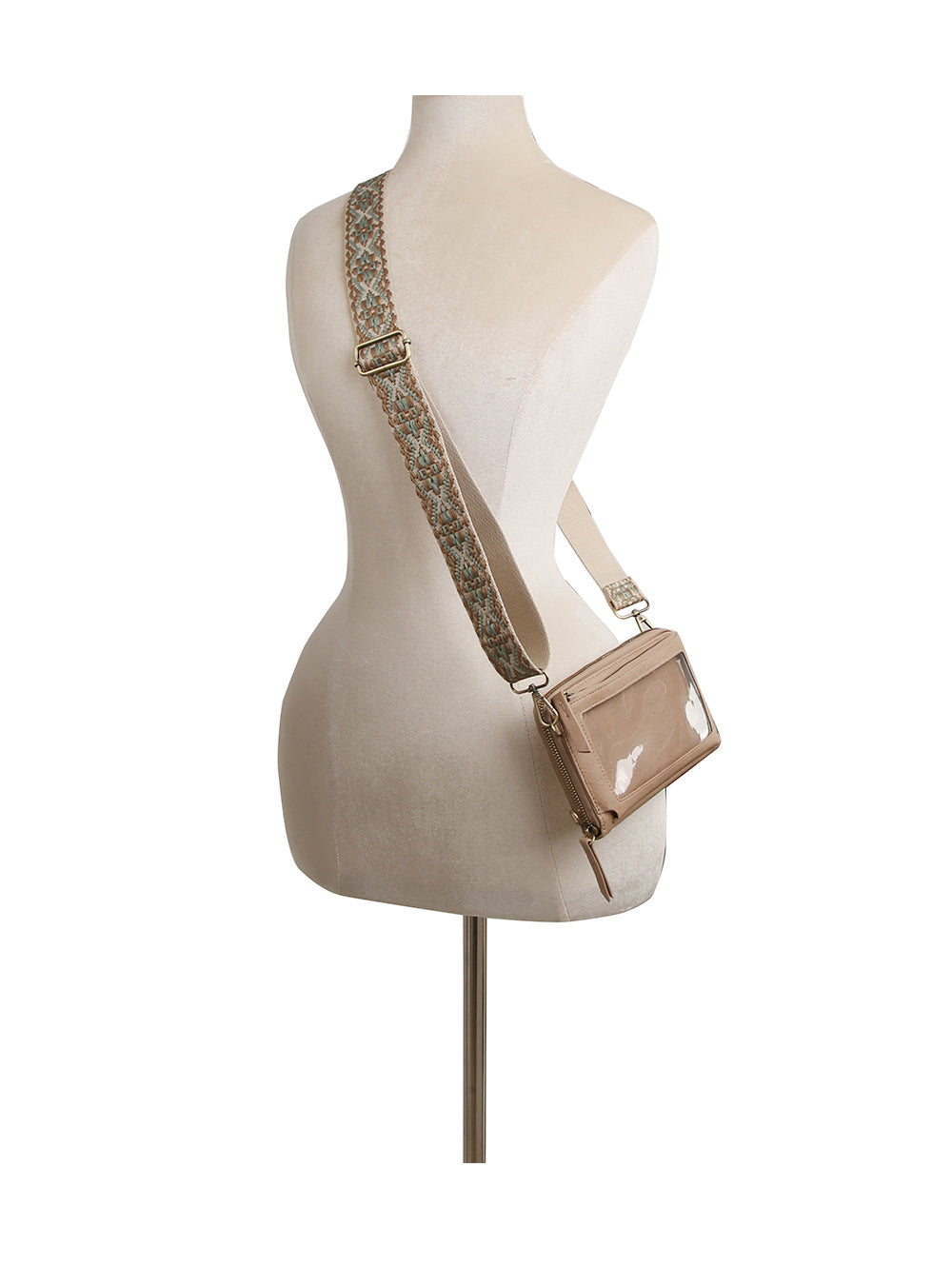 The Petite Multi Compartment Guitar Strap Crossbody, in beige faux leather with a wide patterned detachable strap, is displayed on a white mannequin torso from the back, bag resting at the hip.