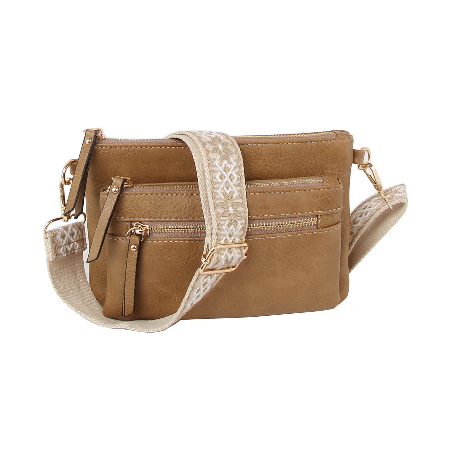 The Guitar Strap Crossbody Sling Handbag is a small tan faux leather bag with three front zippered pockets and a wide, cream geometric-patterned strap.