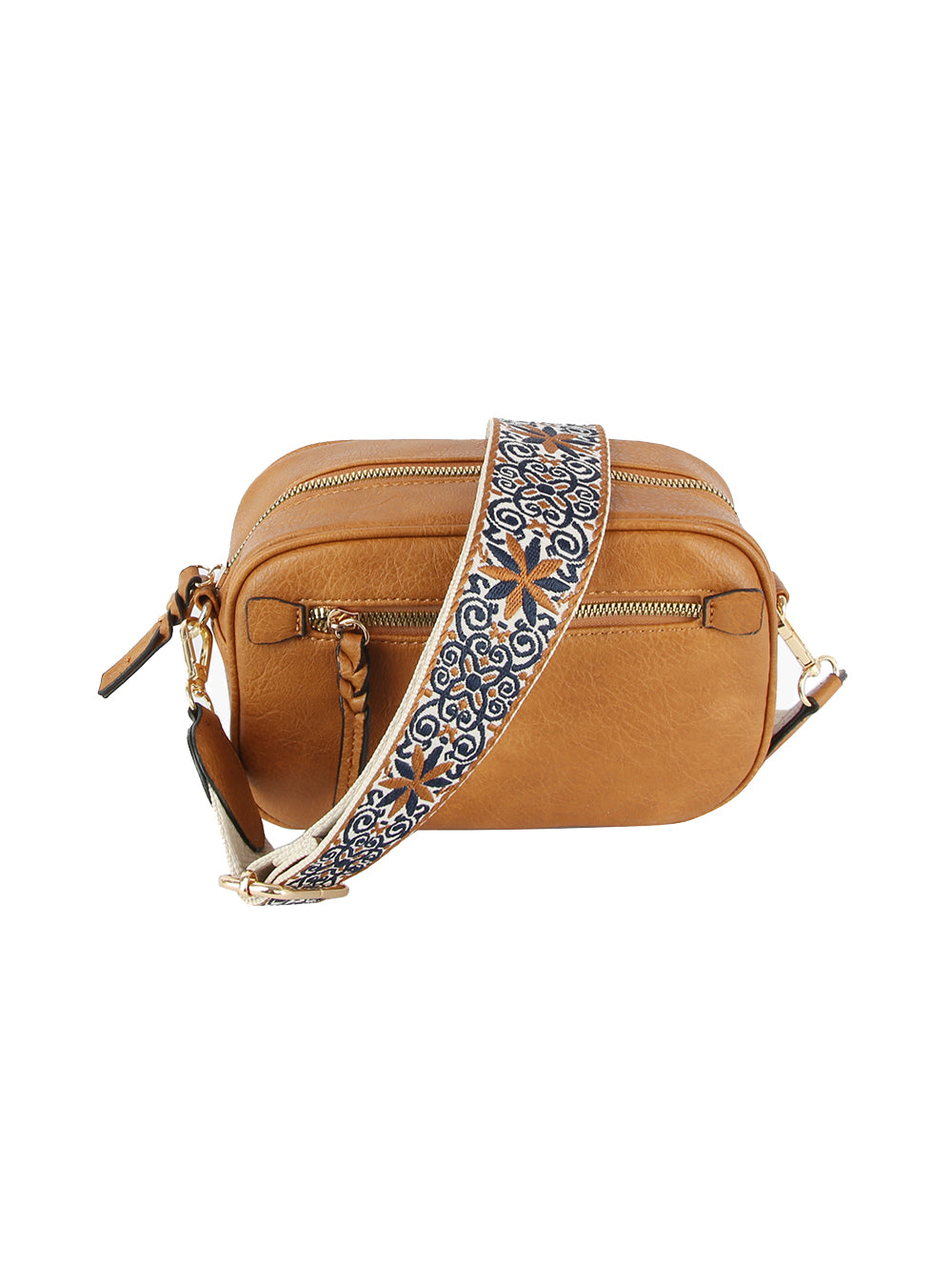 The Guitar Strap Crossbody Sling is a tan faux leather bag with gold-toned hardware and a wide, adjustable blue and white floral strap. It features two main compartments and a braided zipper pull for stylish organization.