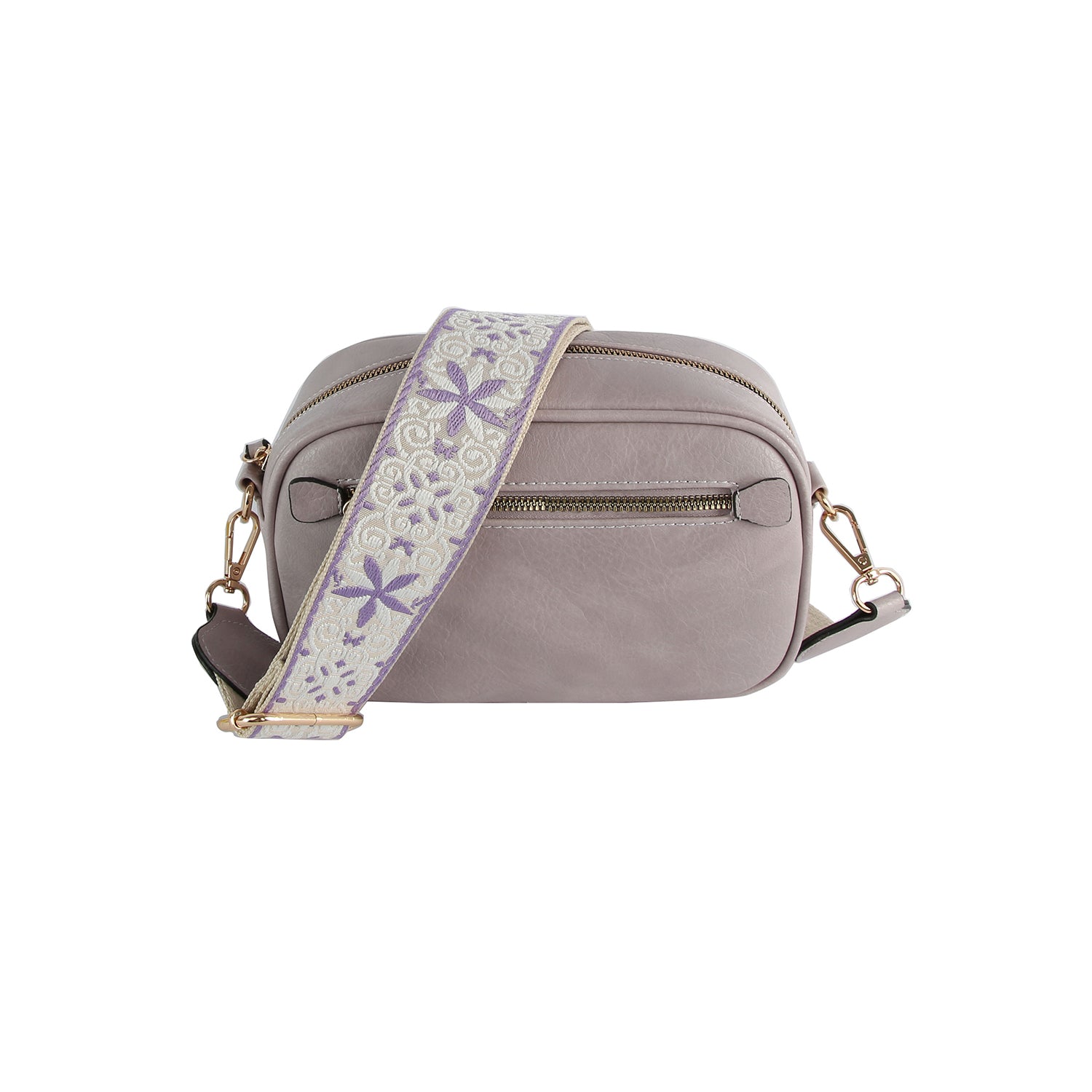 The Guitar Strap Crossbody Sling is a small, light gray faux leather bag with gold-tone hardware and a wide, cream adjustable strap with a purple floral vine pattern. Features include a zippered main compartment and front pocket.