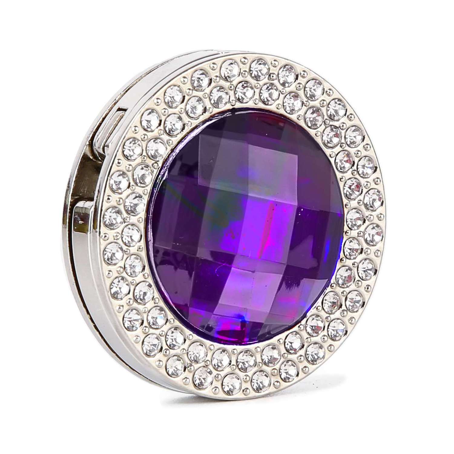 The Gem and Rhinestone Purse Hanger is a round, silver compact featuring a large faceted purple gem at the center, encircled by two rows of clear rhinestones.