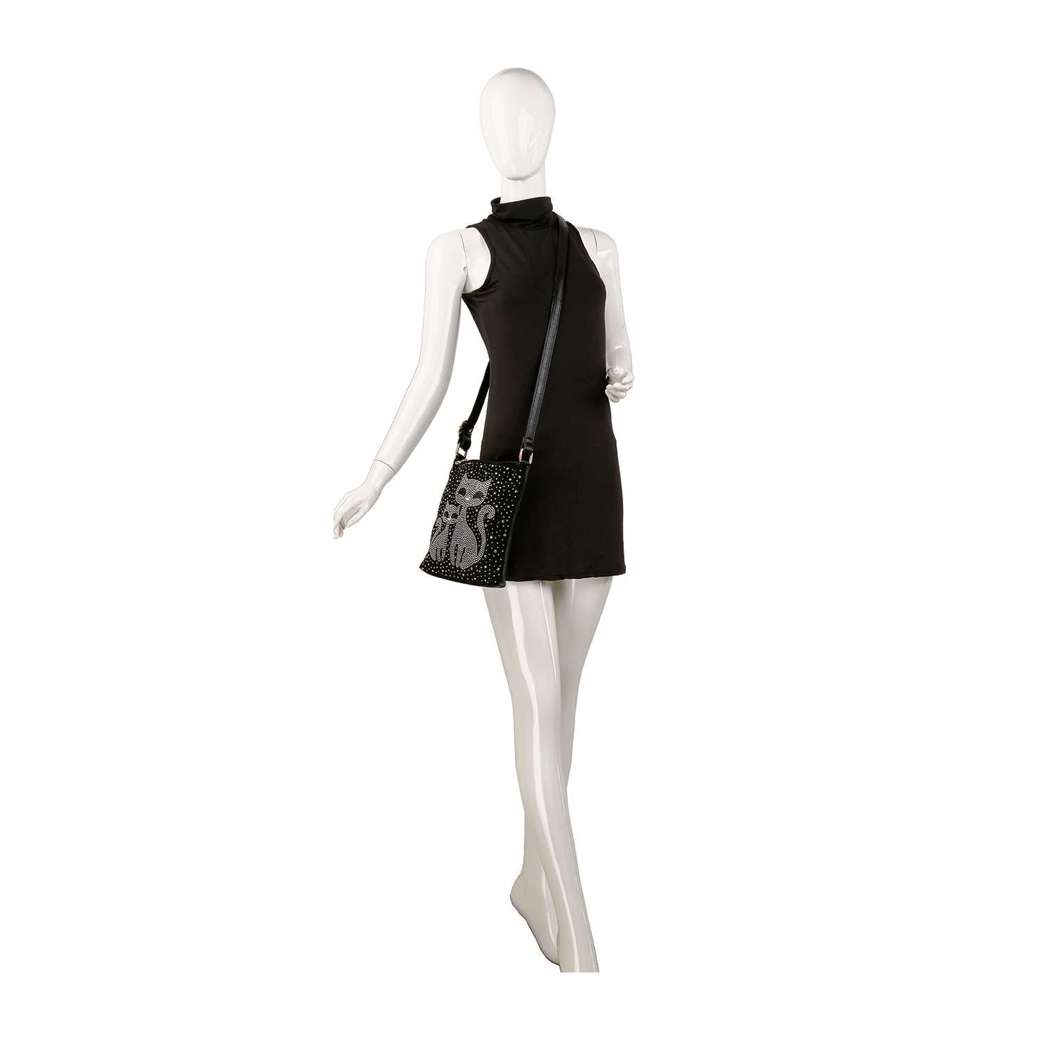 A white mannequin in a sleeveless black mini dress carries the Kitty Cat Sparkling Crossbody Sling with a decorative pattern on its hip, posed against a plain white background.
