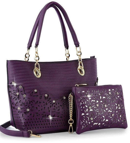 The Rhinestone Accent Accessorized Handbag Set includes a stylish purple faux leather tote with gold hardware, floral laser cutouts, rhinestone accents, and a matching detachable strap, plus a coordinating pouch in front.